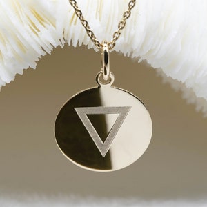 Peut inclure: Collier avec pendentif en or rond orné d'un symbole triangulaire gravé.