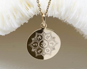 May include: Gold necklace with a round pendant featuring a mandala design with seven Sanskrit symbols, including Om and the number 32.