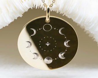 May include: A gold necklace with a round pendant featuring an engraved design of a crescent moon and stars.