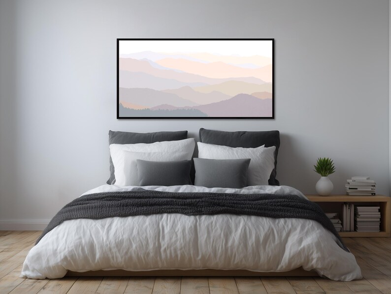 May include: A rectangular wall art print featuring a layered mountain landscape in soft, muted pastel tones of peach, lavender, and grey. The artwork is enclosed in a thin black frame and depicts overlapping mountain silhouettes with a hazy, atmospheric effect.