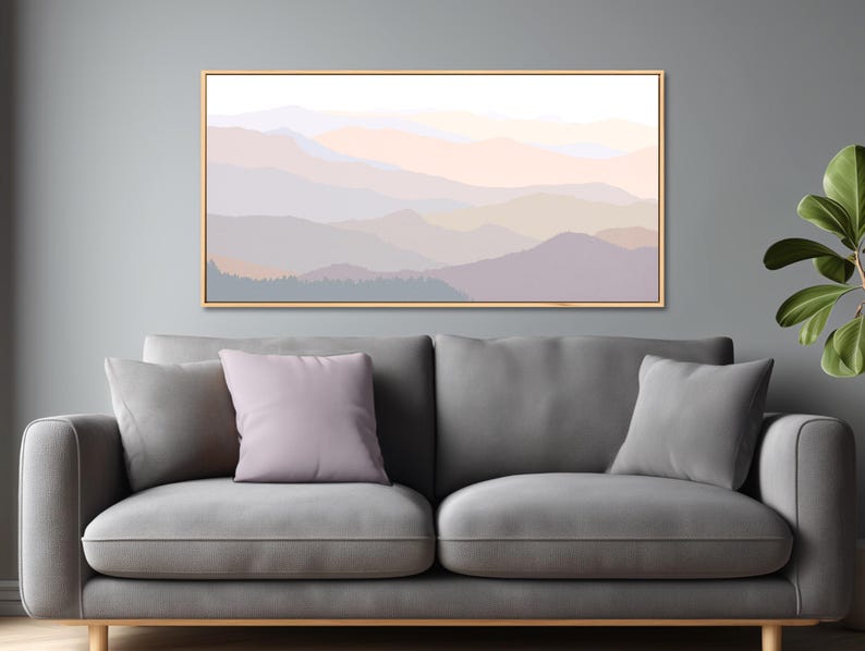 May include: A rectangular wall art piece featuring a layered mountain landscape in soft pastel shades of lavender, peach, and light gray. The artwork is enclosed in a thin, light-colored wooden frame and is displayed horizontally on a wall.
