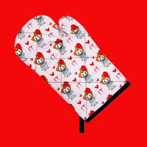 Puede incluir: Manopla de horno blanca con un patrón repetido de un payaso sosteniendo un globo rojo y la palabra "IT" en rojo.