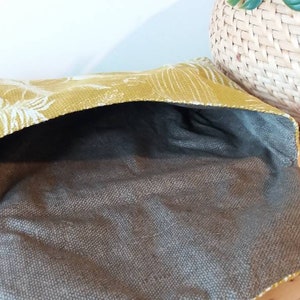 May include: A yellow fabric pouch with a white floral pattern. The pouch is open and the inside is lined with a brown fabric.