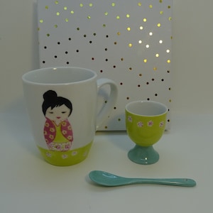 taza y concha de porcelana pintada a mano patrón kokeshi presentado en su caja de cartón blanco con lunares dorados
