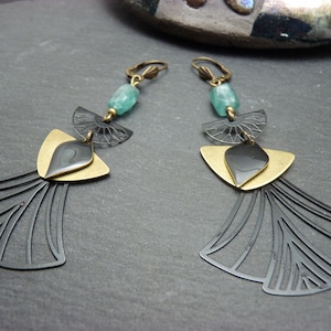 Peut inclure: Une paire de longues boucles d'oreilles pendantes avec un design géométrique. Les boucles d'oreilles présentent des accents en métal noir et or, une pierre de couleur turquoise et un motif en forme d'éventail en bas.