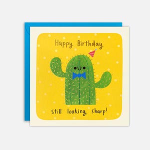 Peut inclure: Carte de vœux d'anniversaire avec un cactus de dessin animé portant un nœud papillon bleu et un chapeau de fête. Le texte "Happy Birthday" et "still looking sharp!" est sur un fond jaune à pois blancs. La carte est sur une enveloppe bleue.