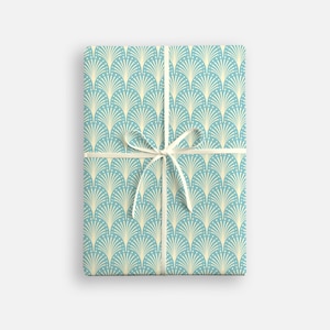 Peut inclure: Un cadeau emballé dans du papier cadeau bleu et crème avec un ruban blanc. Le papier a un motif répétitif de ventilateurs stylisés.