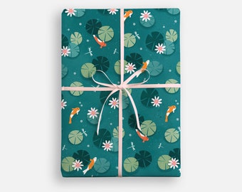 May include: A teal blue gift wrap with a repeating pattern of orange and white fish, green lily pads, and white flowers. The gift wrap is tied with a pink ribbon.