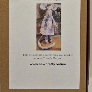 Puede incluir: Caja de kit de manualidades con el texto "MAKE A CHURCH MOUSE" y una imagen de un ratón hecho a mano con un vestido. El kit incluye todo lo necesario para hacer el ratón. También se muestra el sitio web www.sewcrafty.online.