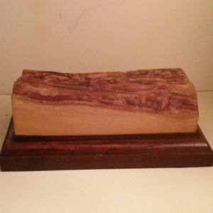 Könnte beinhalten: Eine Holzkiste mit einer natürlichen Holzplatte und einem dunklen Holzsockel. Die Platte hat ein einzigartiges Maserungsmuster.