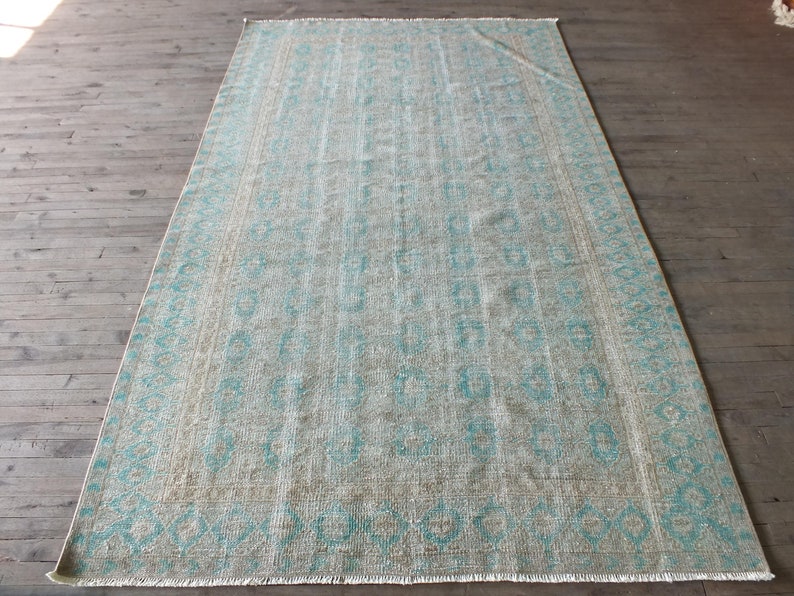 K&ouml;nnte beinhalten: Ein hellblauer und beigefarbener Teppich mit Fransen. Der Teppich hat einen verblassten, Vintage-Look.