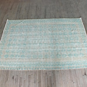 K&ouml;nnte beinhalten: Ein hellblauer und beigefarbener Teppich mit einem verblassten, Vintage-Look.