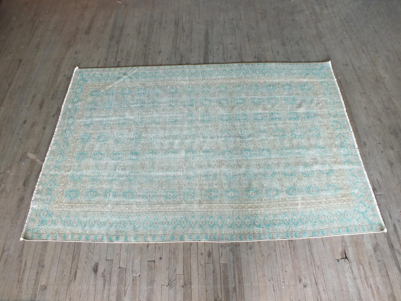 K&ouml;nnte beinhalten: Ein hellblauer und beigefarbener Teppich mit einem verblassten, Vintage-Look.