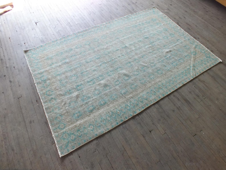 K&ouml;nnte beinhalten: Ein hellblauer und wei&szlig; gemusterter Teppich mit einem dezenten geometrischen Design. Der Teppich ist aus einem weichen, gewebten Material gefertigt und hat einen Used-Look.