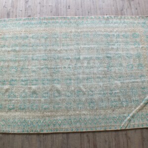 K&ouml;nnte beinhalten: Ein hellblauer und beiger Teppich mit geometrischem Muster. Der Teppich hat einen Fransenrand.