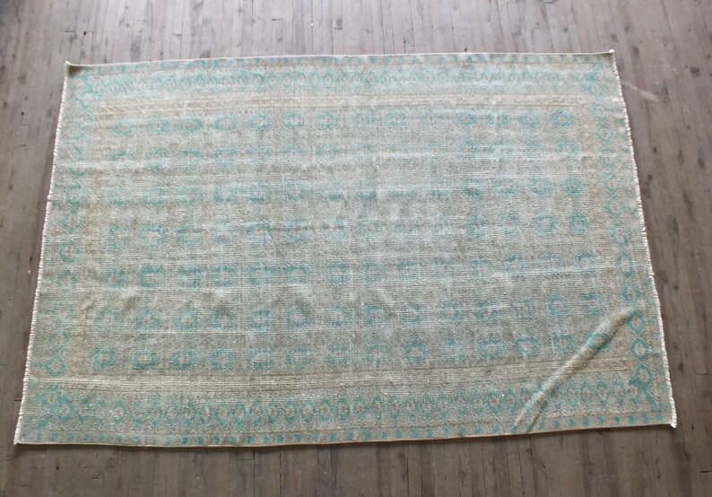 K&ouml;nnte beinhalten: Ein hellblauer und beiger Teppich mit geometrischem Muster. Der Teppich hat einen Fransenrand.