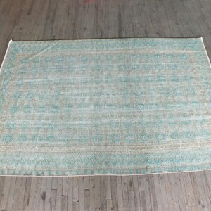 K&ouml;nnte beinhalten: Ein hellblauer und beiger Teppich mit geometrischem Muster. Der Teppich hat einen verblassten, Vintage-Look.