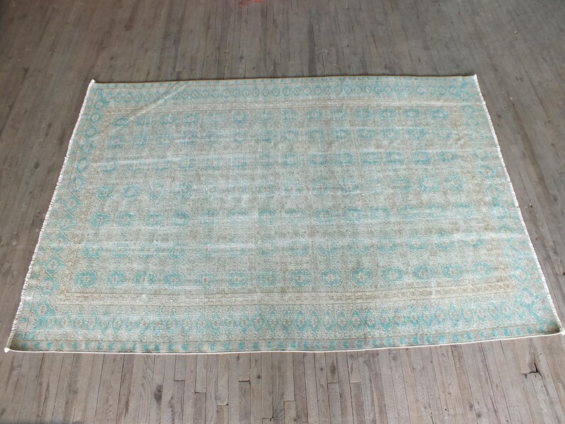 K&ouml;nnte beinhalten: Ein hellblauer und beiger Teppich mit geometrischem Muster. Der Teppich hat einen verblassten, Vintage-Look.