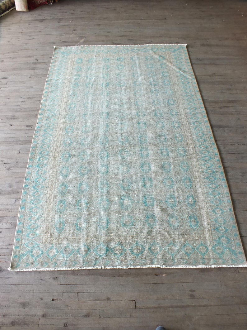 K&ouml;nnte beinhalten: Ein hellblauer und wei&szlig; gemusterter Teppich mit Fransen. Der Teppich hat einen verblassten, Vintage-Look.