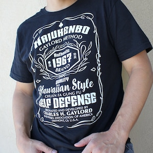 May include: Black t-shirt with a white graphic design featuring the text "HAJUHENBO GAYLORD METHOD", "Authentic 1967 BRAND", "Hawaiian Style", "CHUẨN FA GUNG FU", and "SELF DEFENSE". The graphic also includes a clover symbol and the text "ORIGINATED AND DEVELOPED BY CHARLES H. GAYLORD KAYUKENBO ASSOCIATION OF AMERICA FREMONT, CA U.S.A."