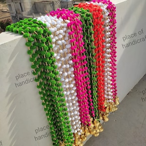May include: A collection of colorful garlands with pom-poms and gold bells. The garlands are in shades of green, white, pink, red, and orange. The text "place of handicraft" is visible in the image.