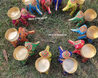 May include: A set of 12 colorful elephant candle holders with gold accents. Each elephant is decorated with intricate patterns and has a small, round candle holder on its back.