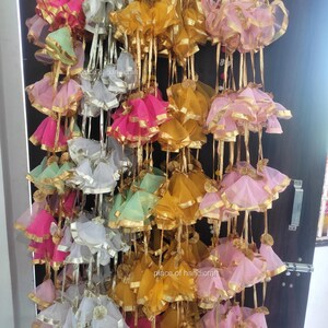 May include: A display of colorful fabric garlands with gold trim. The garlands are made of multiple layers of sheer fabric and are tied together with gold ribbon. The garlands are hanging from a door frame.