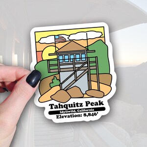 May include: A sticker featuring a cartoon illustration of a lookout tower with a small American flag on top. The tower is on a hill with rocks and trees. The text "Tahquitz Peak" is below the image, with the text "Idyllwild, California" and "Elevation: 8,846'" below that.