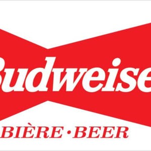 May include: A rectangular sticker featuring the Budweiser logo. The logo consists of the word "Budweiser" in white, bold, sans-serif font, set against a red bow-tie shape. Below, the words "BIÈRE • BEER" are in red.