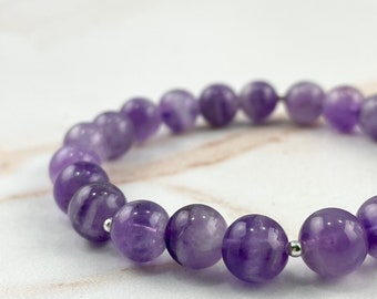 Puede incluir: Un brazalete de cuentas de amatista púrpura con detalles plateados.