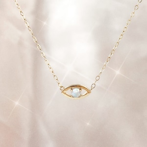May include: A gold chain necklace with a delicate eye pendant featuring a white opal gemstone.