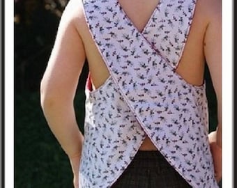 May include: A white sleeveless top with a floral pattern and criss-cross straps in the back. The top is designed for a child and has the text "Taille 2/3 ans" printed on the front.