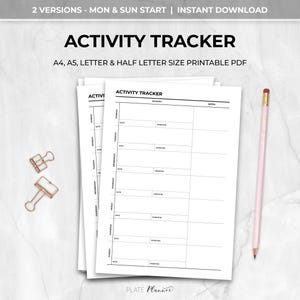 May include: A stack of white printable activity tracker sheets with the title "ACTIVITY TRACKER". The sheets include sections for date, activity, duration, and notes. A pink pencil and gold paper clips are also visible.