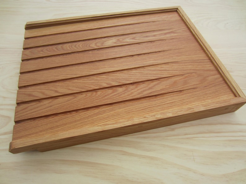 K&ouml;nnte beinhalten: Ein Holztablett mit hellbrauner Oberfl&auml;che und gerillter Oberfl&auml;che. Das Tablett hat einen erh&ouml;hten Rand um den Umfang.