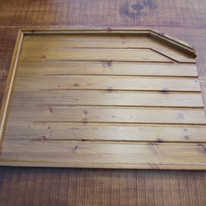 May include: A wooden panel with a decorative edge, featuring a light brown stain and a horizontal wood grain pattern.