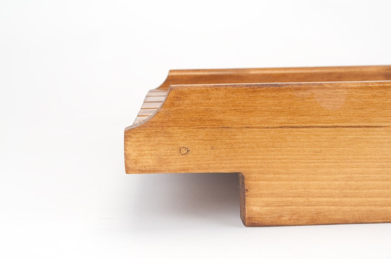 May include: A wooden serving tray with a natural finish. The tray has a rectangular shape with rounded edges and a raised lip.