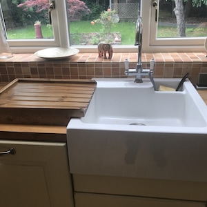 May include: A white porcelain kitchen sink with a chrome faucet and a wooden cutting board.