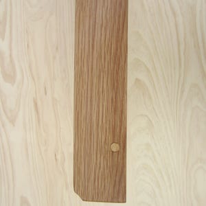 May include: A close-up of a light brown wood plank with a knot hole. The wood has a natural grain pattern.