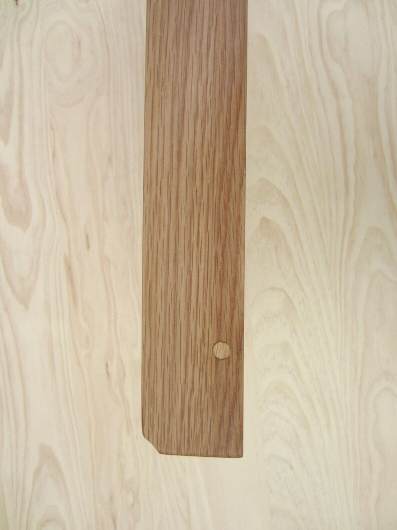 May include: A close-up of a light brown wood plank with a knot hole. The wood has a natural grain pattern.