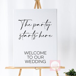 May include: A white canvas sign on a wooden easel with the text "The party starts here" in a cursive font. Below, in a block font, it reads "WELCOME TO OUR WEDDING". A small logo is in the bottom right corner.