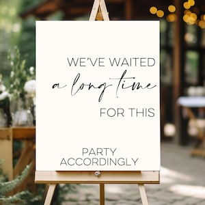 May include: White sign with black text that reads "We've waited a long time for this party accordingly". The sign is on a wooden easel.