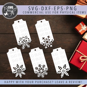 Op de afbeelding: Witte papieren cadeaulabels met sneeuwvlokuitsparingen. De labels hebben een klein gaatje aan de bovenkant om te rijgen. De afbeelding bevat ook de tekst "SVG-DXF-EPS-PNG COMMERCIAL USE FOR PHYSICAL ITEMS" en "HAPPY WITH YOUR PURCHASE? LEAVE A REVIEW!"