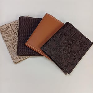 May include: Four rectangular passport holders arranged in a fan shape. The first is beige with a snakeskin pattern, the second is dark brown with a woven texture, the third is smooth tan leather, and the fourth is dark brown with an embossed floral pattern.
