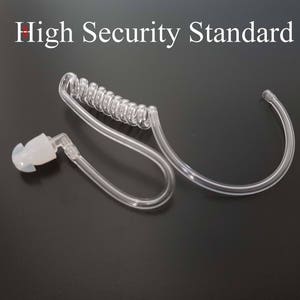 Könnte beinhalten: Ein transparentes Kunststoff-Ohrstück mit einem Spiralkabel und einem weißen Ohrstöpsel. Das Ohrstück ist für diskrete Kommunikation konzipiert.