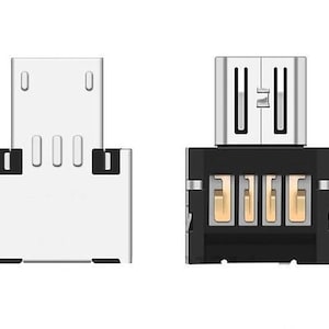 Könnte beinhalten: Ein silberner Micro-USB-Adapter mit einem schwarzen Stecker. Der Adapter hat vier goldfarbene Pins am Stecker.