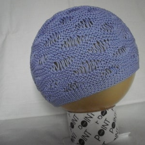 May include: A light blue knitted hat with a lacy pattern. The hat is displayed on a white mannequin head.