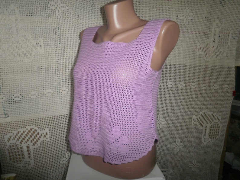 May include: A sleeveless crocheted top in a light purple color. The top has a square neckline and a delicate crocheted pattern.