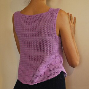 May include: A sleeveless crochet top in a light purple color. The top has a delicate, open-weave pattern and a scalloped hem.