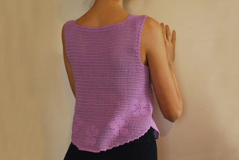 May include: A sleeveless crochet top in a light purple color. The top has a delicate, open-weave pattern and a scalloped hem.
