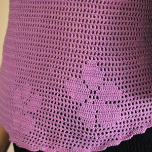 May include: A close-up of a pink crocheted top with a scalloped hem.